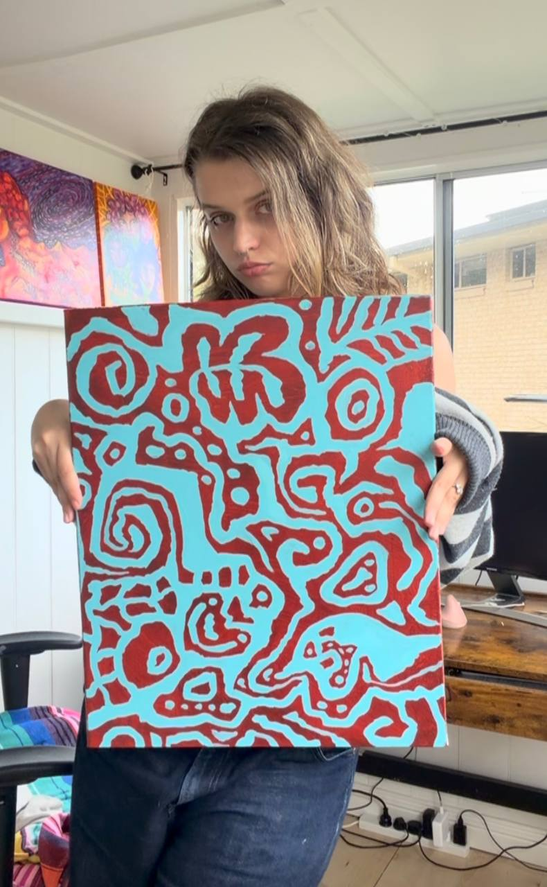 Ana holding her red and turquoise painting in her studio